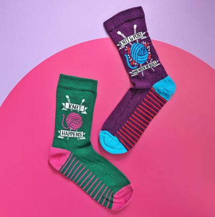 A pair of socks for knitters saying knit happens, and knit, purl and rock and roll.